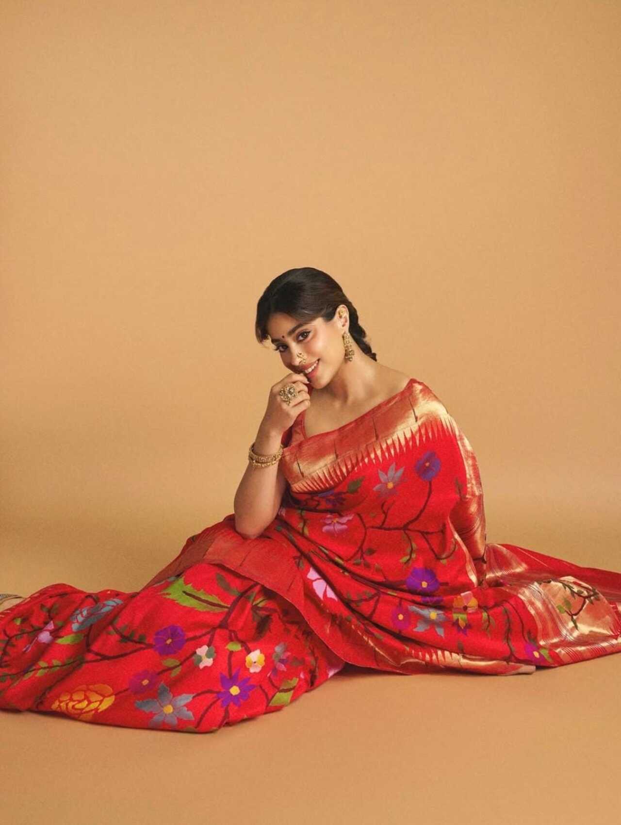 Janhvi Kapoor turns heads in a vibrant red Paithani adorned with multicoloured floral motifs. The rich silk texture paired with her modern blouse design adds a contemporary edge.